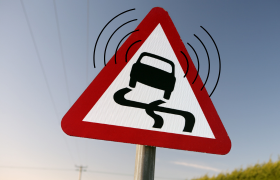 Panneau routier montrant une voiture en dérapage qui émet des ondes cellulaires